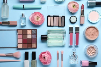 Flat lay composition with different makeup products and beautiful spring flowers on light blue background