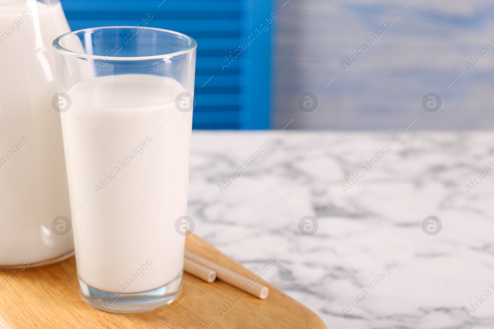 Photo of Glassware with tasty milk on white marble table, closeup. Space for text