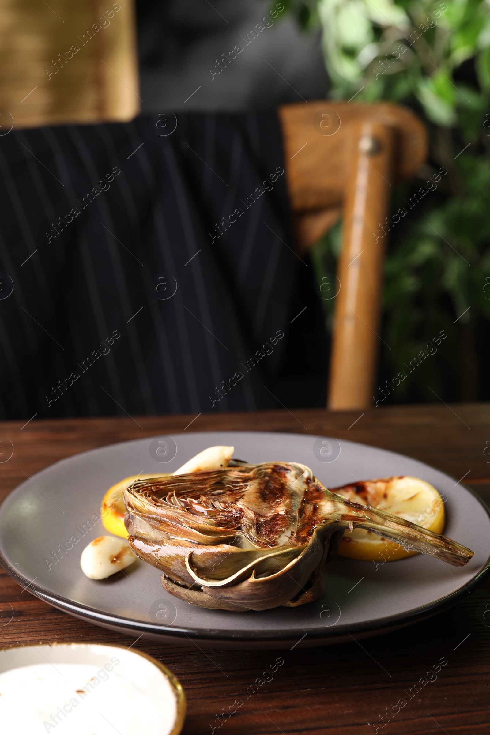 Photo of Tasty grilled artichoke served on wooden table