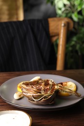 Tasty grilled artichoke served on wooden table