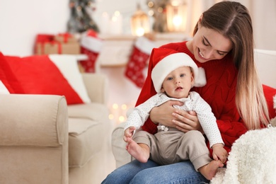 Happy mother with cute baby in room decorated for Christmas holiday