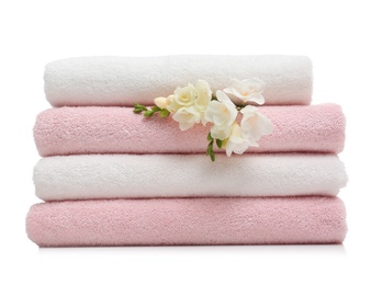 Stack of clean folded towels with flowers on white background