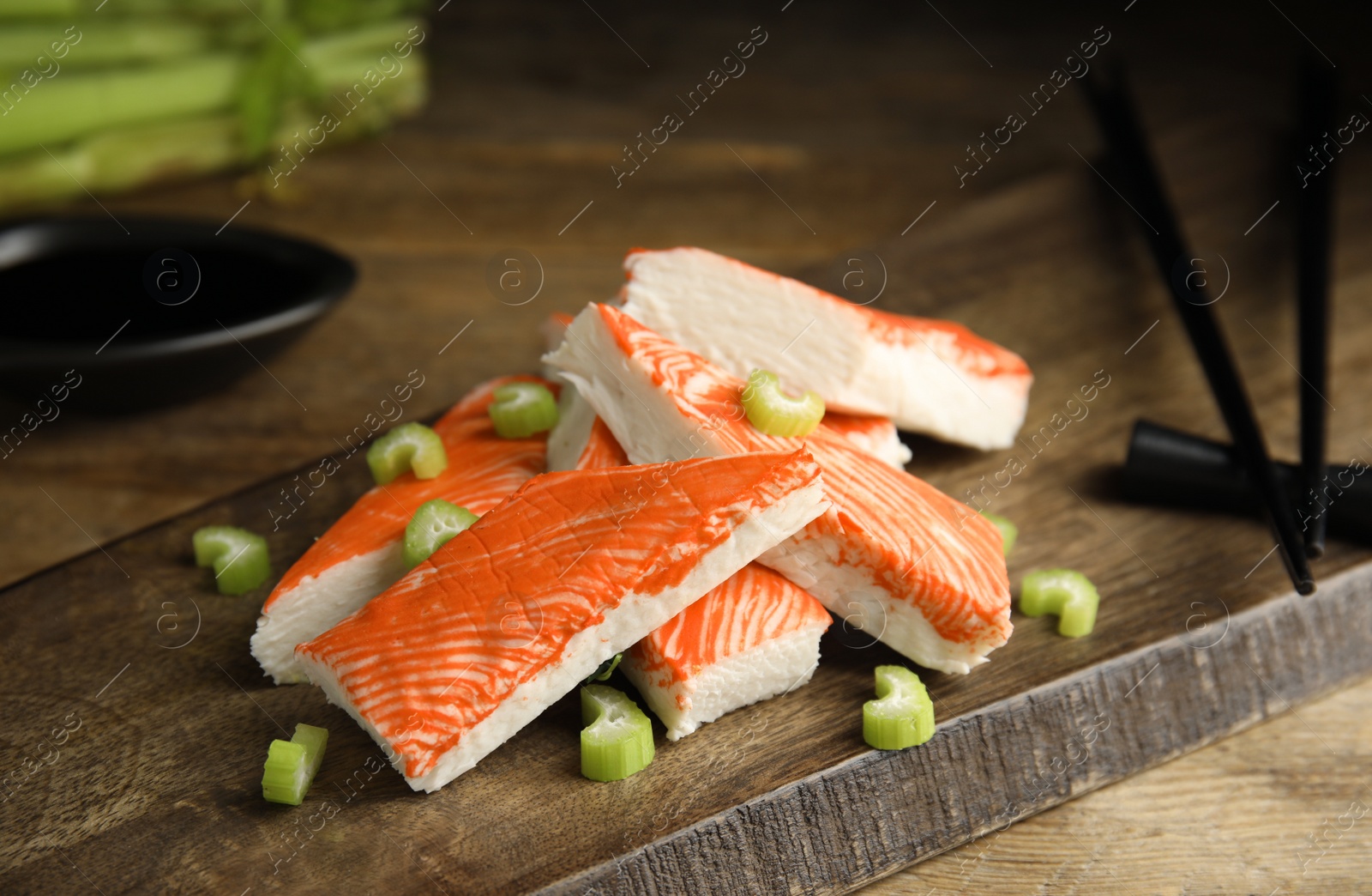 Photo of Fresh crab sticks with celery served on wooden table, closeup