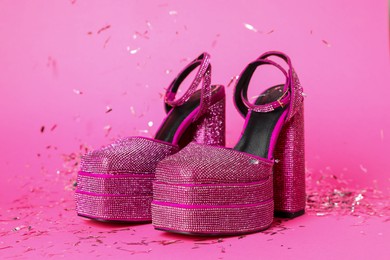 Photo of Fashionable punk square toe ankle strap pumps and confetti on pink background. Shiny party platform high heeled shoes