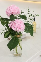 Photo of Beautiful pink hortensia flowers in vase on kitchen counter