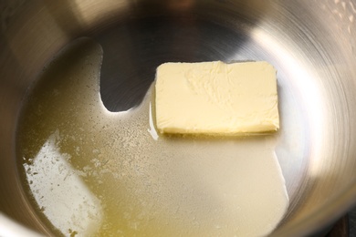 Photo of Piece of melting butter in pot, closeup