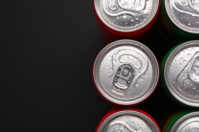 Photo of Energy drinks in wet cans on dark background, top view. Space for text