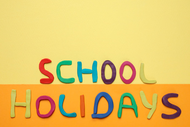 Photo of Phrase School Holidays made of modeling clay on color background, top view