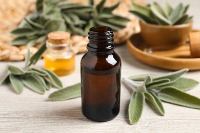 Photo of Bottle of essential sage oil and leaves on wooden table