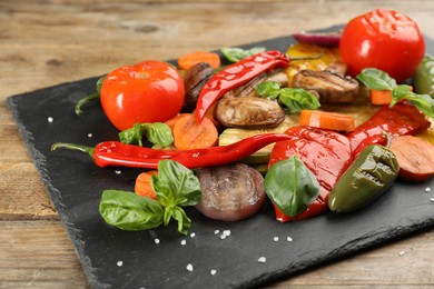 Photo of Delicious grilled vegetables with basil on wooden table, closeup