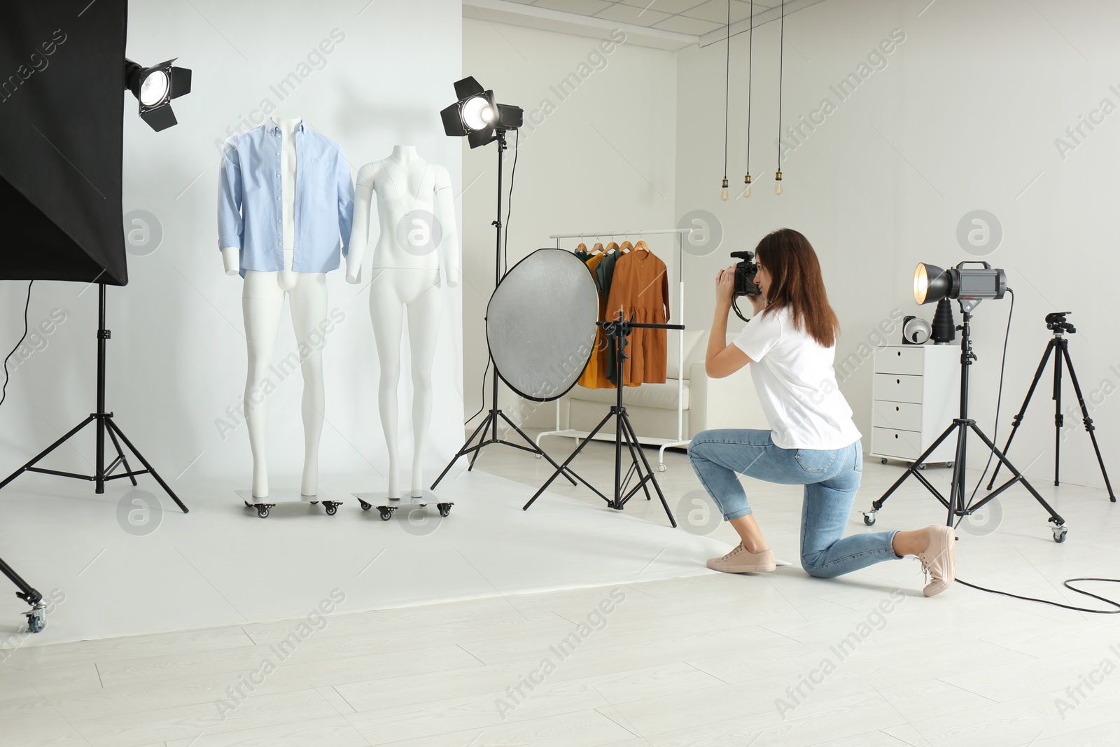 Photo of Professional photographer taking picture of ghost mannequins with modern clothes in photo studio