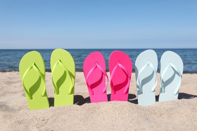 Stylish colorful flip flops on beach sand