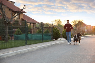 Young man walking his Caucasian Shepherd dog outdoors