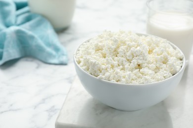 Photo of Delicious fresh cottage cheese in bowl on white marble table