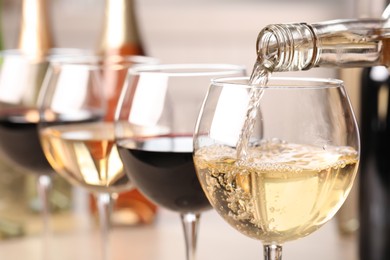 Photo of Pouring white wine from bottle into glass, closeup