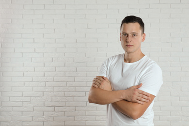 Photo of Handsome young man near white brick wall. Space for text
