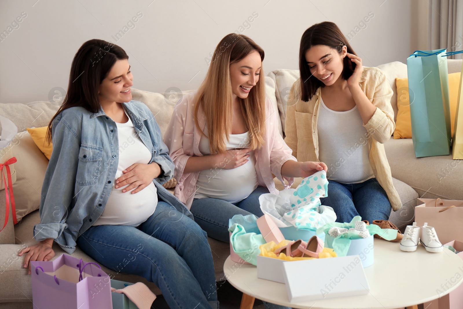 Photo of Happy pregnant women spending time together in living room after shopping