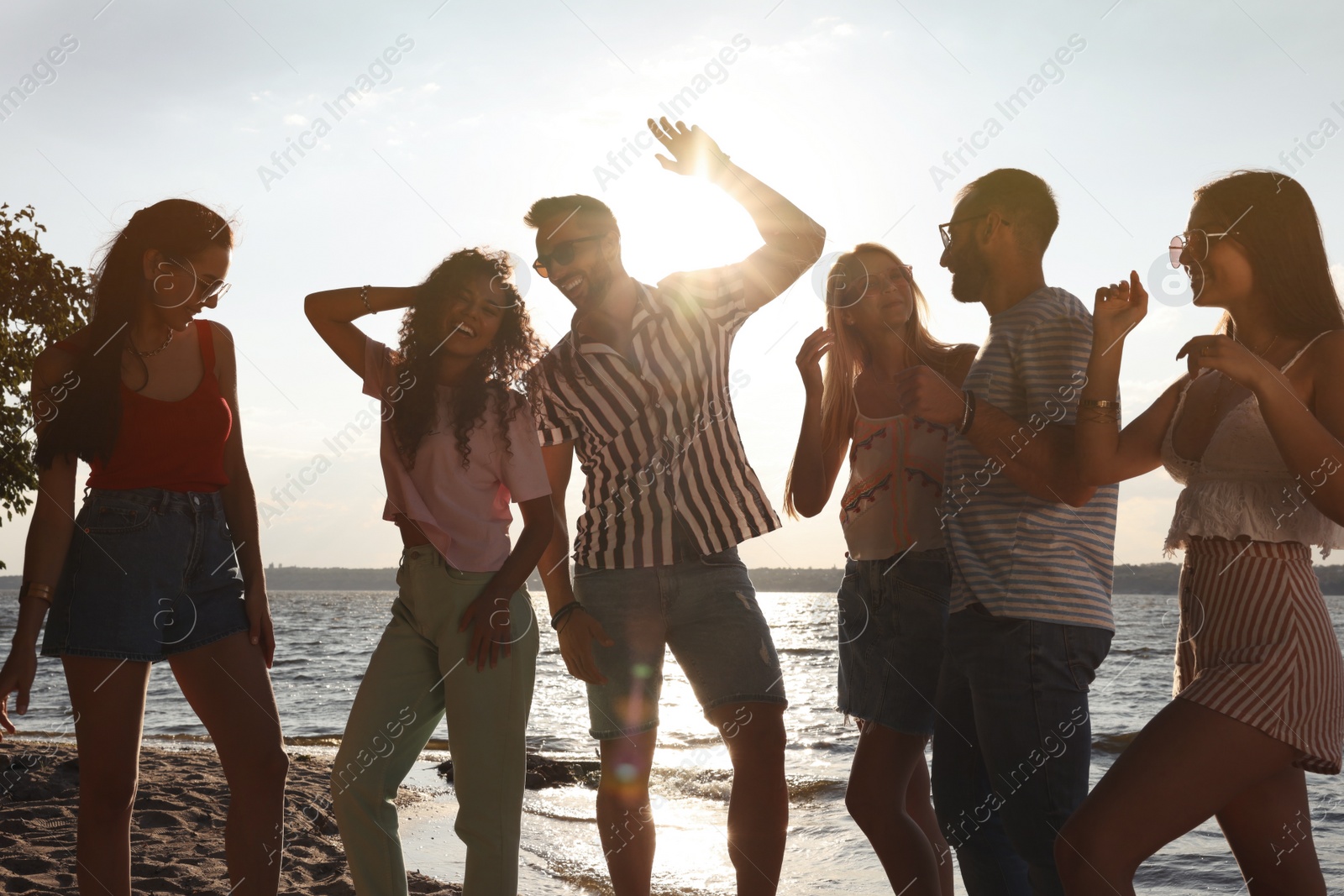 Photo of Group of friends having fun near river at summer party