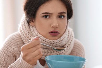 Photo of Sick young woman eating soup to cure flu