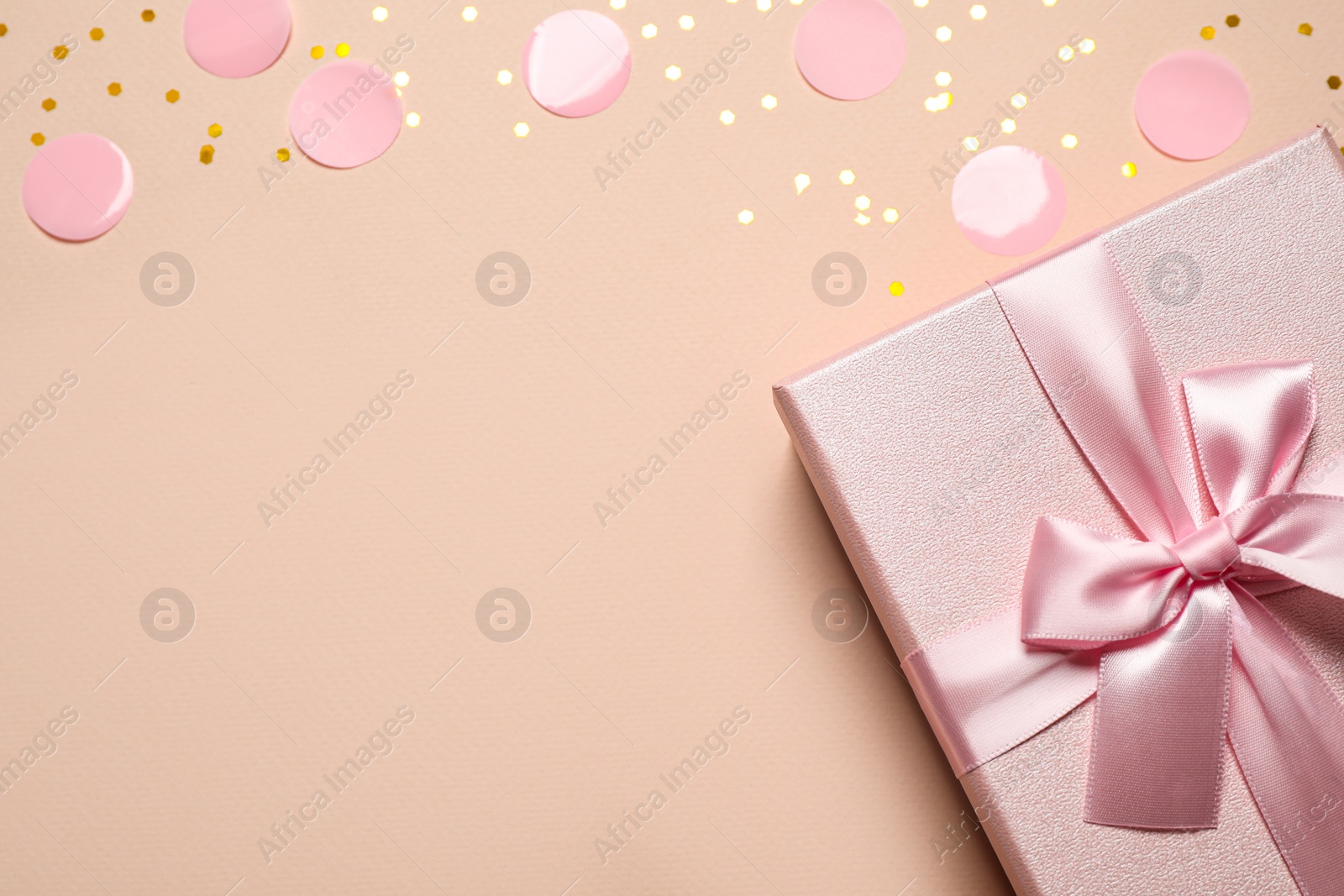 Photo of Pink gift box and confetti on color background, top view. Space for text