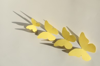 Yellow paper butterflies on light grey background, top view
