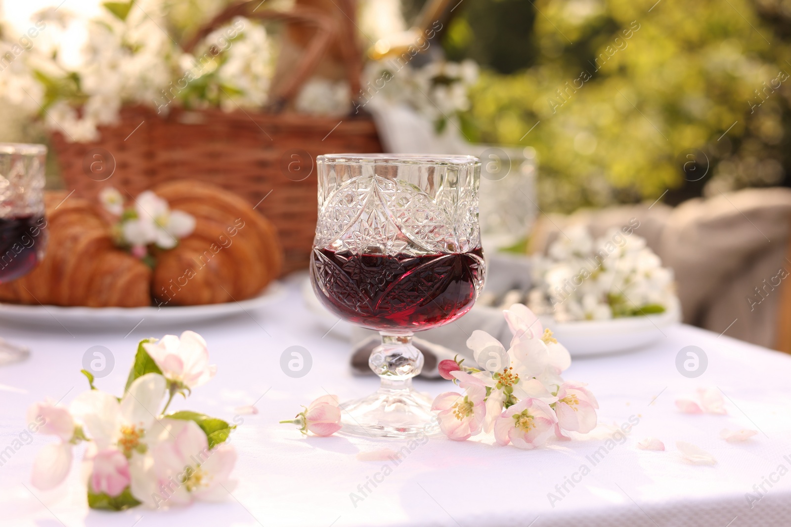 Photo of Stylish table setting with beautiful spring flowers, wine and croissants in garden