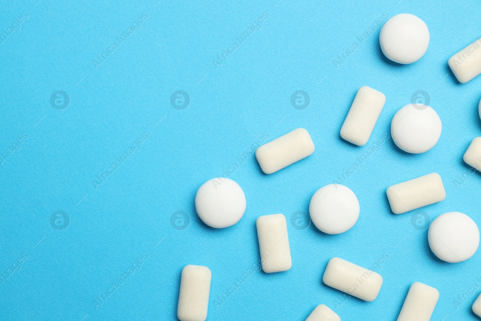 Photo of White bubble gums on blue background, flat lay. Space for text