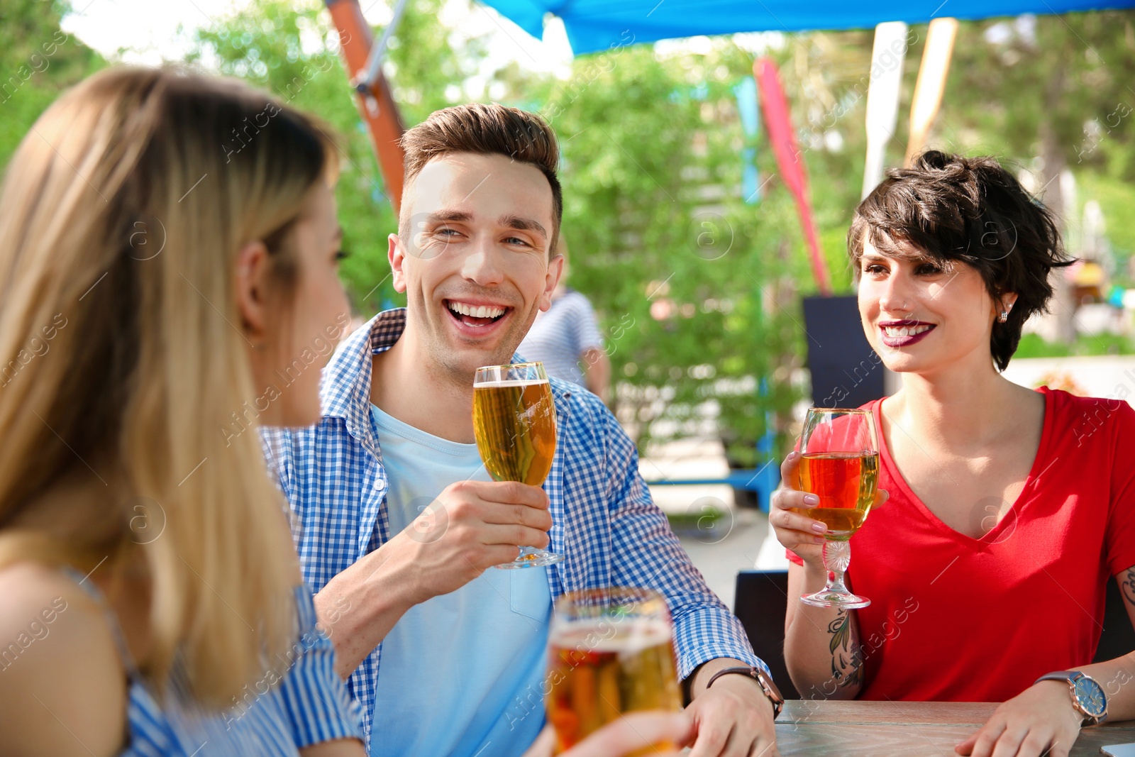 Photo of Young people with glasses of cold beer at table