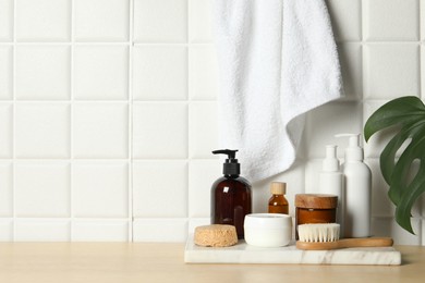 Photo of Different bath accessories and personal care products on wooden table near white tiled wall, space for text