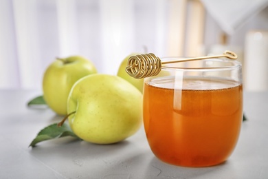 Photo of Glass of honey, apples and dipper on light table