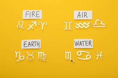 Zodiac triplicity. Four elements and corresponding signs on yellow background, flat lay