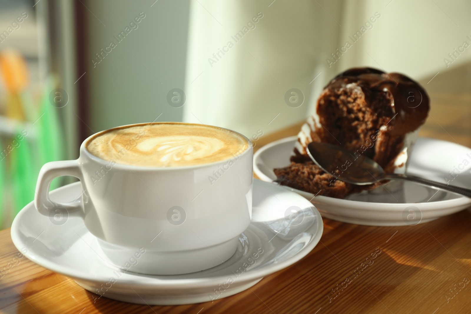 Photo of Cup of fresh aromatic coffee and cupcake at table in cafe