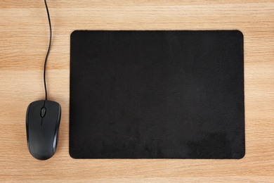 Blank pad and computer mouse on wooden background, top view