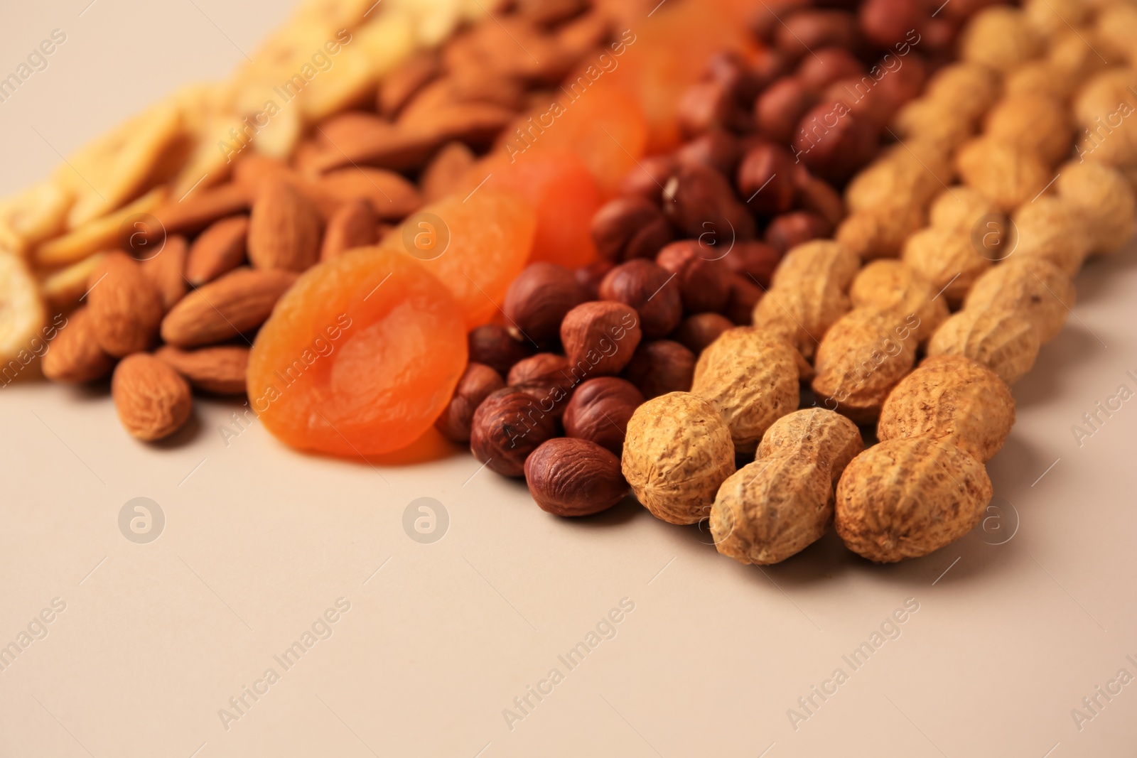 Photo of Mix of delicious dried nuts and fruits on beige background, closeup