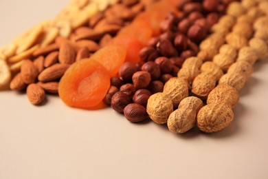 Photo of Mix of delicious dried nuts and fruits on beige background, closeup