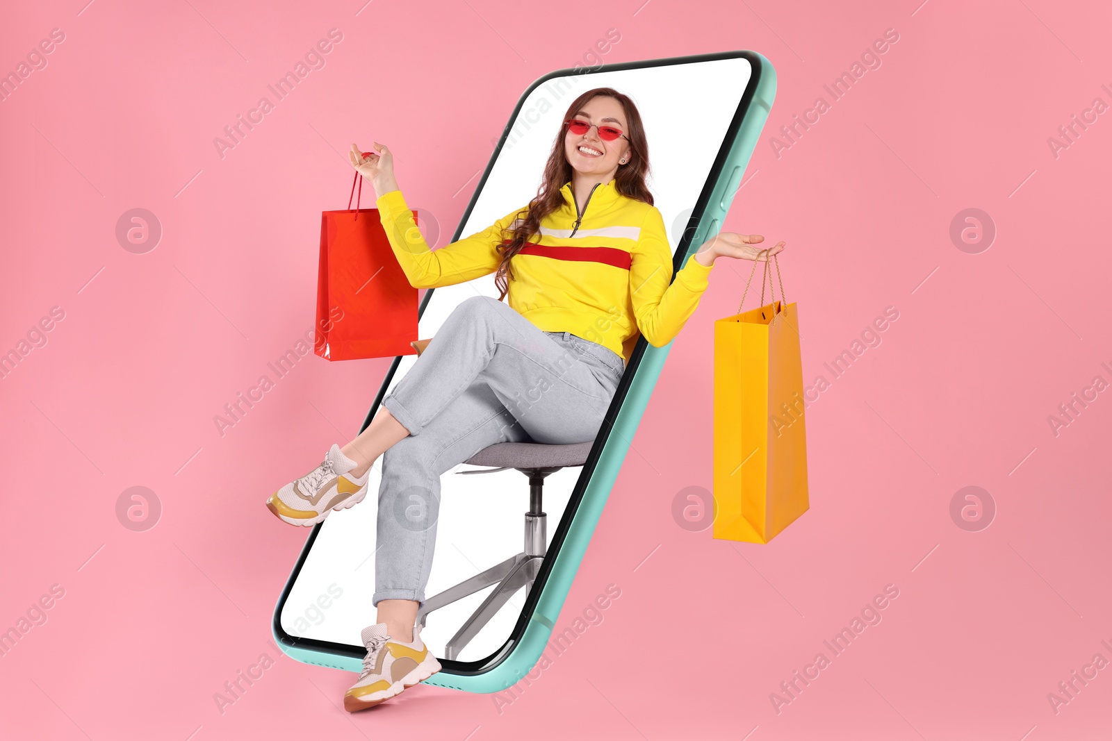 Image of Online shopping. Happy woman with paper bags on chair looking out from smartphone against pink background