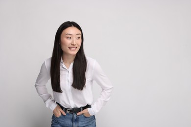 Portrait of smiling woman on light background. Space for text