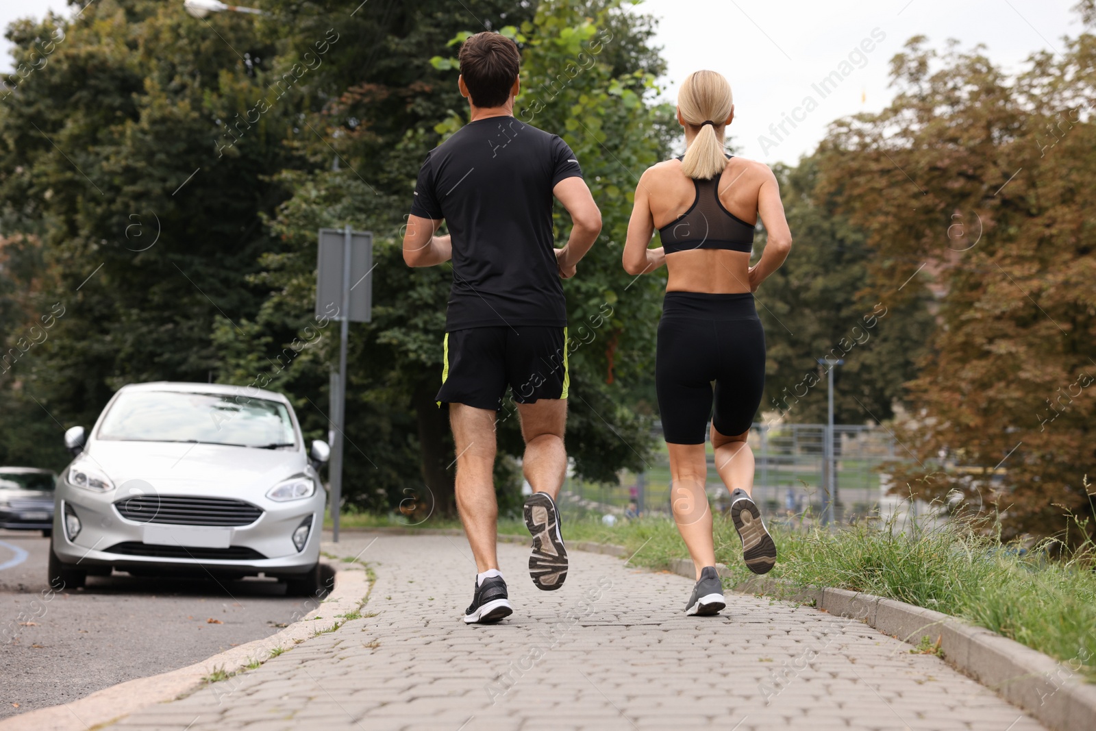 Photo of Healthy lifestyle. Sporty couple running outdoors, back view