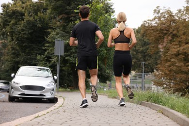 Healthy lifestyle. Sporty couple running outdoors, back view