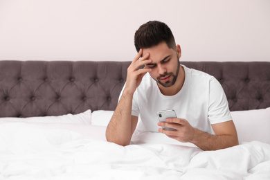 Photo of Young man addicted to smartphone in bed at home