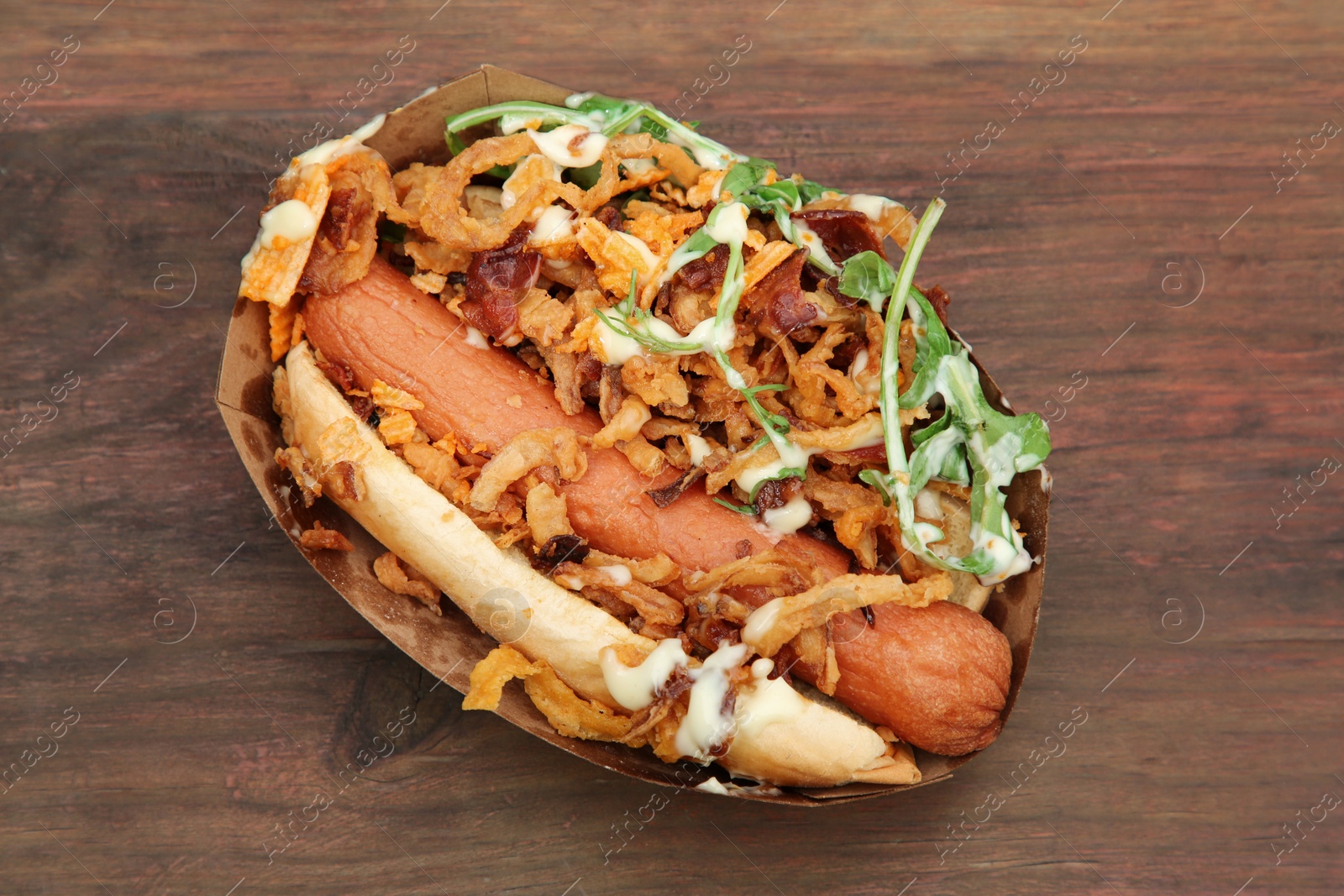 Photo of Fresh delicious hot dog on wooden table, top view