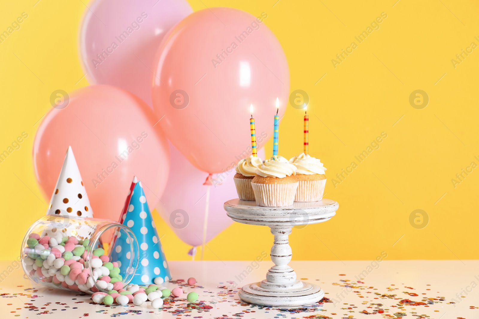 Photo of Composition with birthday cupcakes and balloons on table