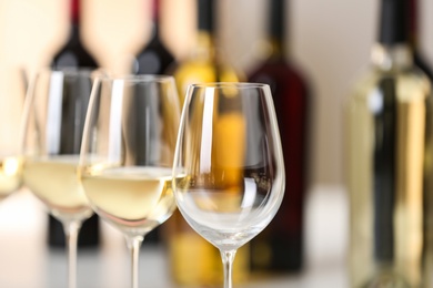 Photo of Row of wine glasses and blurred bottles on background, space for text