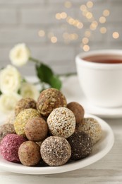 Photo of Delicious vegan candy balls on white wooden table against blurred lights