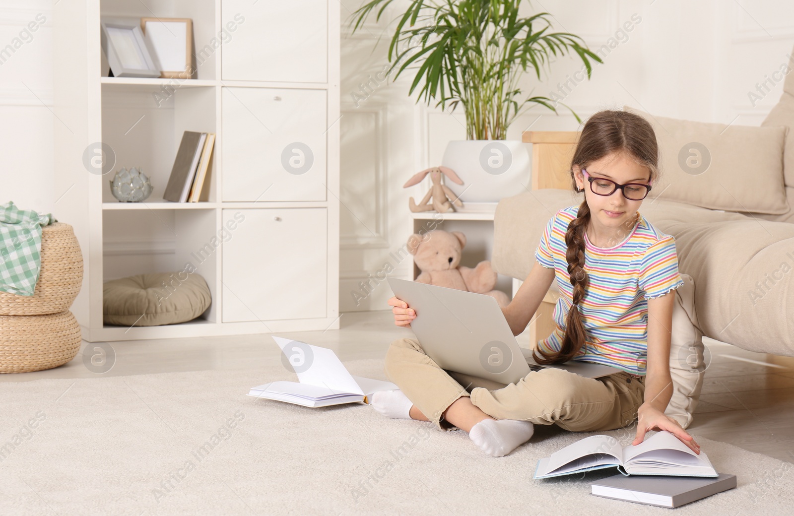 Photo of Girl with laptop and books sitting on floor at home