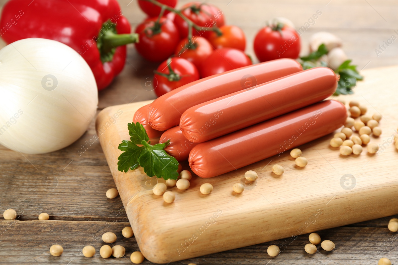 Photo of Fresh raw vegetarian sausages, soybeans and vegetables on wooden table, closeup