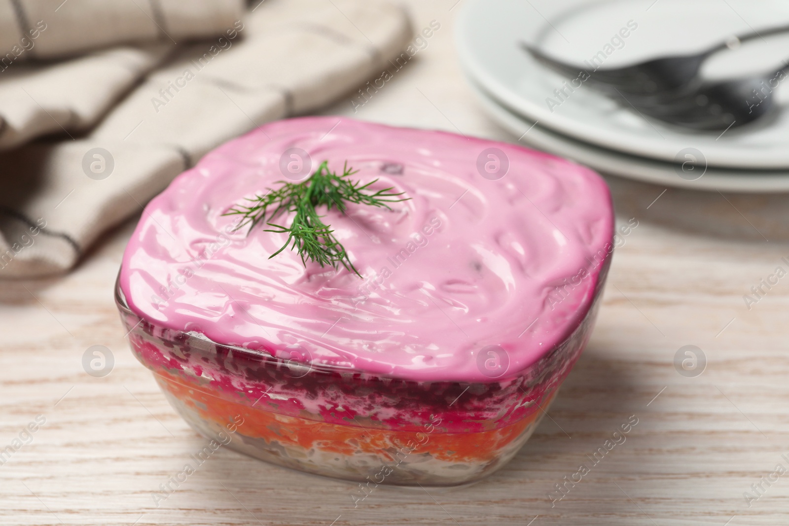 Photo of Herring under fur coat salad on white wooden table, closeup. Traditional Russian dish