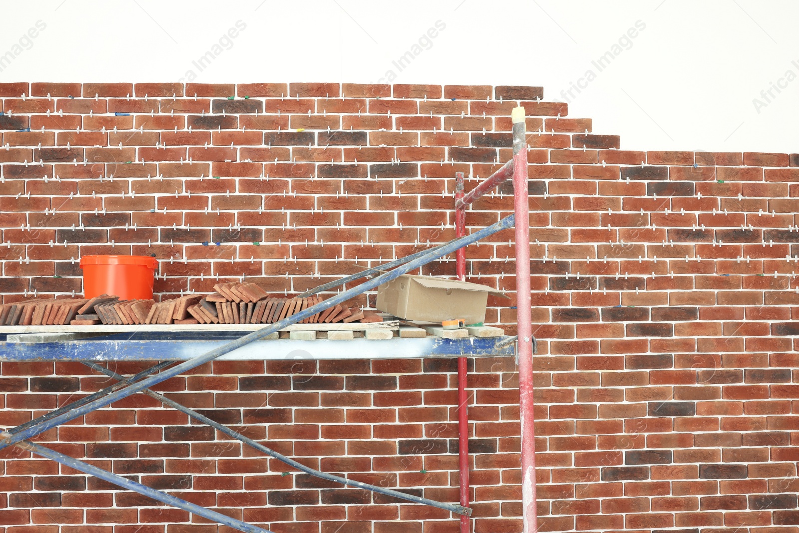 Photo of Scaffolding near wall with decorative bricks and tile leveling system indoors