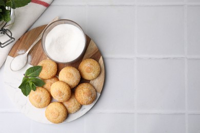 Photo of Tasty sweet sugar cookies and mint on white tiled table, top view. Space for text