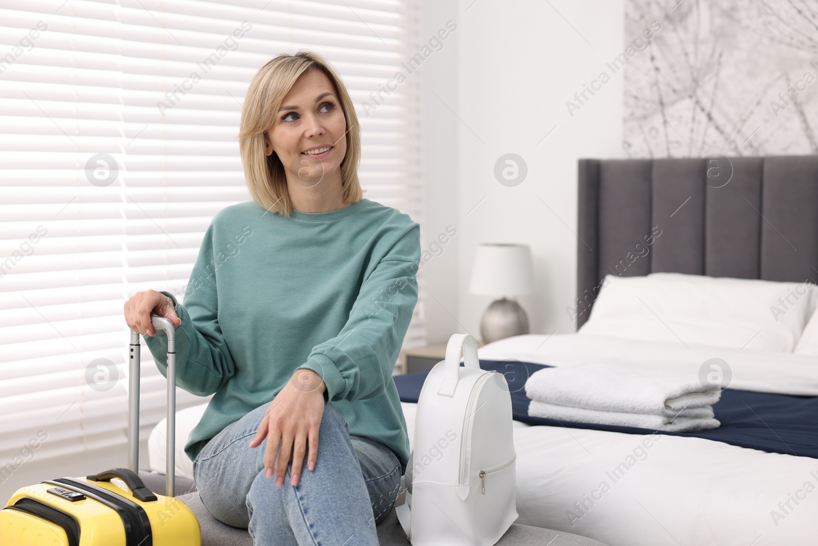 Photo of Smiling guest with backpack and suitcase in stylish hotel room